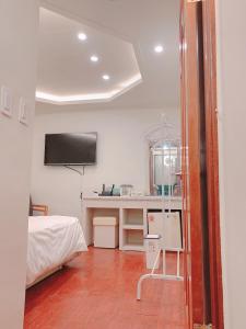 a room with a bed and a desk with a television at Dongdaemun Karrot Hostel in Seoul