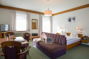 ein Hotelzimmer mit einem Bett, einem Tisch und einem Sofa in der Unterkunft Haus Friedrichsburg - Bergbahnen bis November inklusive in Bad Hofgastein