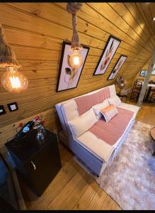a living room with a couch in a wooden wall at Chalés Laraland in Campos do Jordão