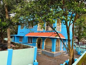 a blue house with a tree in front of it at Supreme Stay Varkala in Varkala