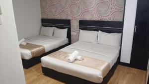 two beds in a hotel room with white sheets at Bluebell Hotel skudai in Kempas