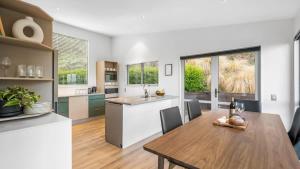 a kitchen and dining room with a wooden table at Opuke House- Free Parking- Lake views- BBQ- Spa in Queenstown