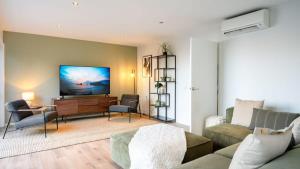 a living room with a couch and a tv at Opuke House- Free Parking- Lake views- BBQ- Spa in Queenstown