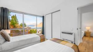 a bedroom with two beds and a large window at Opuke House- Free Parking- Lake views- BBQ- Spa in Queenstown
