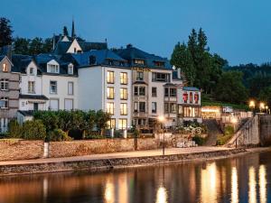 a large white building next to a river at night at Villa Steps from Castle in Bouillon