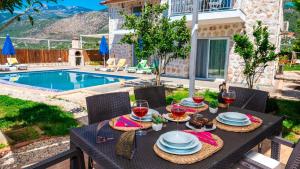 a table with food and wine glasses on it next to a pool at Villa atılgan in Kaş +2 photos