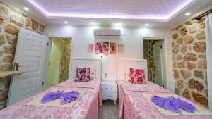two beds in a room with pink and purple sheets at Villa atılgan in Kaş