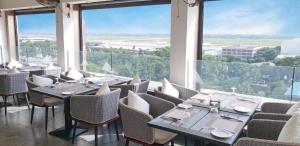 a restaurant with tables and chairs and large windows at The Zabeer Dhaka in Dhaka