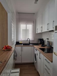 kuchnia z białymi szafkami i miską owoców na ladzie w obiekcie Apartment Amelia w mieście La Mata