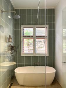 a green tiled bathroom with a tub and two windows at The Paarl Grand in Paarl +32 photos