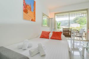 芒通« La Grande Résidence » Vue Mer, Piscine的卧室里有一张白色的大床，上面放着橙色的枕头 更多15张照片