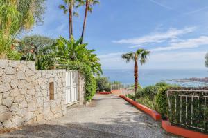 a driveway with a stone wall and palm trees at "Le Clos des Guillons" Piscine, Vue imprenable, Parkings in Menton