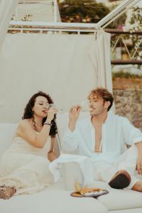 a bride and groom drinking wine while sitting on a bed at Hotel Ferdinando Beach & Thermal Spa in Ischia