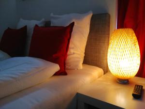 Una cama con almohadas rojas y blancas y una lámpara. en INSIDE Five, en Zúrich