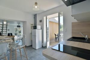 a kitchen with a refrigerator and a table with chairs at La Campagne Émeraude - Proche du Mont Saint-Michel in Baguer-Morvan