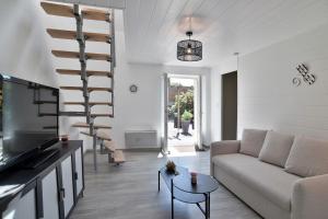 a living room with a couch and a spiral staircase at La Campagne Émeraude - Proche du Mont Saint-Michel in Baguer-Morvan