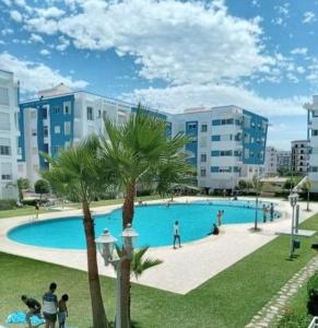 Una gran piscina con palmeras y edificios. en Amira luxury home, en Martil