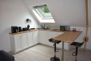 a kitchen with white cabinets and a skylight at Bords de l'Aure, Meublé de tourisme 3 étoiles in Bayeux