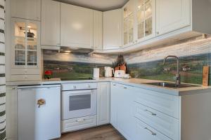a white kitchen with white cabinets and a sink at Holiday house VilAna with Jacuzzi - Happy Rentals in Puconci