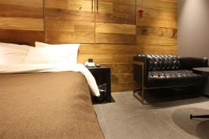 a bedroom with a bed and a leather chair at Hotel Avant in Cheonan