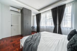 a bedroom with a white bed and large windows at S21 Mellow Phromphong in Bangkok