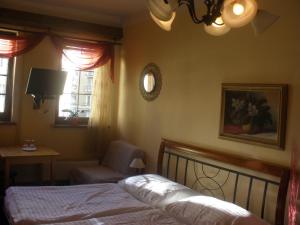 a bedroom with a bed and a chair and two windows at Penzion Vysehrad in Český Krumlov