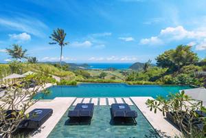 an infinity pool with lounge chairs and a view of the ocean at Selong Selo Resort and Residences in Selong Belanak