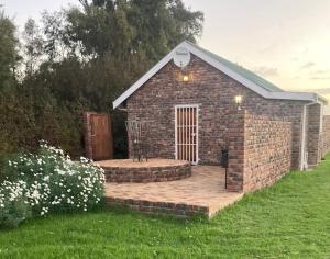 a small brick building with a patio in a yard at Rivier-Plesier Cottage at Riggton River Farm in Bonnievale +18 photos
