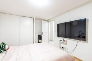 una camera bianca con un grande letto e una TV di L'Escapade du Lac - Proche du Lac Léman a Évian-les-Bains