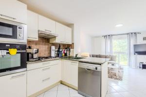 una cucina con mobili bianchi e un forno a piano cottura di L'Escapade du Lac - Proche du Lac Léman a Évian-les-Bains