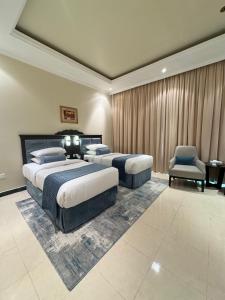 a hotel room with two beds and a chair at AG Hotel in Abu Dhabi