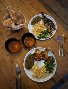 four plates of food on a wooden table at Ghar El Melh Outdoors in Raʼs al Jabal
