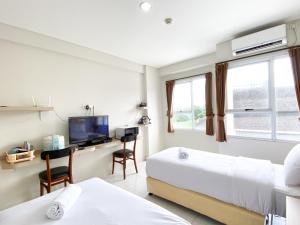 a hotel room with two beds and a desk and a tv at Good Choice and Comfy Studio (No Kitchen) at Elvis Tower Apartment By Travelio in Cikarang