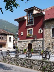a red building with wheels in front of it at Hotel Mestas in Arenas de Cabrales