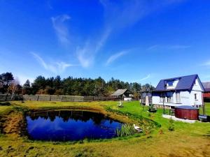 a farm house with a pond in the yard at DAGNA summer house in Šunupis