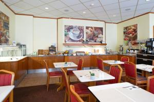 a restaurant with tables and chairs and a kitchen at Taste Smart Hotel Lampertheim in Lampertheim