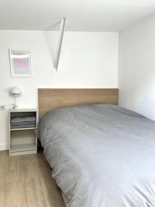 a white bedroom with a bed and a night stand at 735 Cosy studio mezzanine près de Paris et métro in Bagnolet