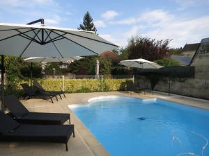 a swimming pool with two chairs and an umbrella at Logis Hotel De France in La Chartre-sur-le-Loir