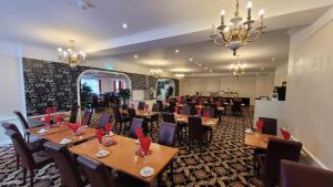 a restaurant with wooden tables and chairs and a chandelier at Heathlands Hotel in Bournemouth