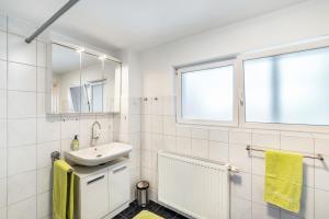a white bathroom with a sink and a window at Ferienhaus Albert in Bühl +21 photos