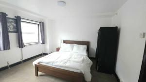 a bedroom with a bed with white sheets and a window at London Stockwell Station Apartment in London