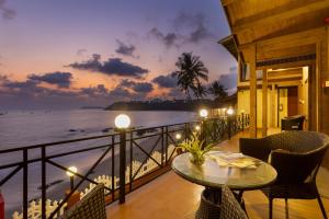 a balcony with a table and chairs and the ocean at Bogmallo Beach Resort in Bogmalo