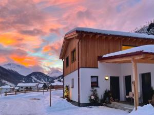 a house in the snow with a sunset at TYROL PURElife Lodges in Sankt Jakob in Defereggen