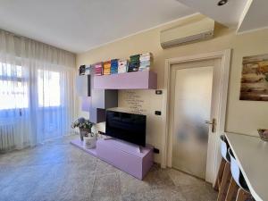 a living room with a tv and a purple shelf at I piedi nell'acqua in Finale Ligure