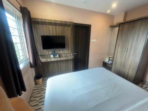 Un dormitorio con una cama blanca y un televisor de pantalla plana. en Hotel Joy, en Jamshedpur 14 fotos más
