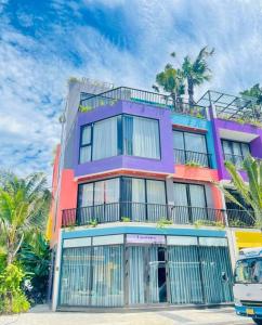 a colorful building with palm trees in front of it at Flamingo Hải Tiến - Lavender Villa 6 phòng ngủ in Nam Khê