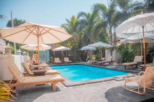 a swimming pool with lounge chairs and umbrellas at Color Cottage in Gili Islands