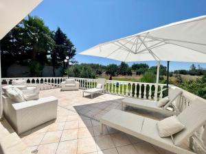 a patio with white furniture and an umbrella at Villa Rachele con piscina in Balestrate