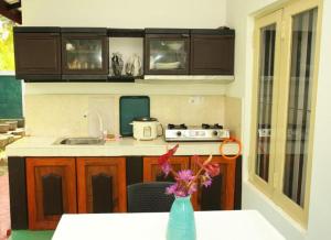 a kitchen with a table and a vase with flowers in it at Villa Laceleaf in Induruwa