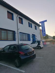 ein schwarzes Auto, das auf einem Parkplatz vor einem Gebäude geparkt ist in der Unterkunft H&G LOZOYUELA in Lozoyuela